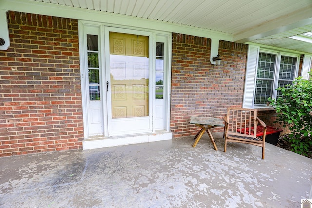 entrance to property with covered porch and brick siding