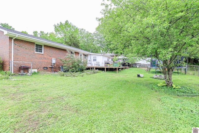 view of yard with a trampoline, a deck, and a fenced backyard