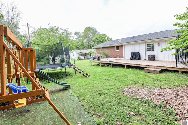 view of yard featuring a playground, a deck, and a trampoline