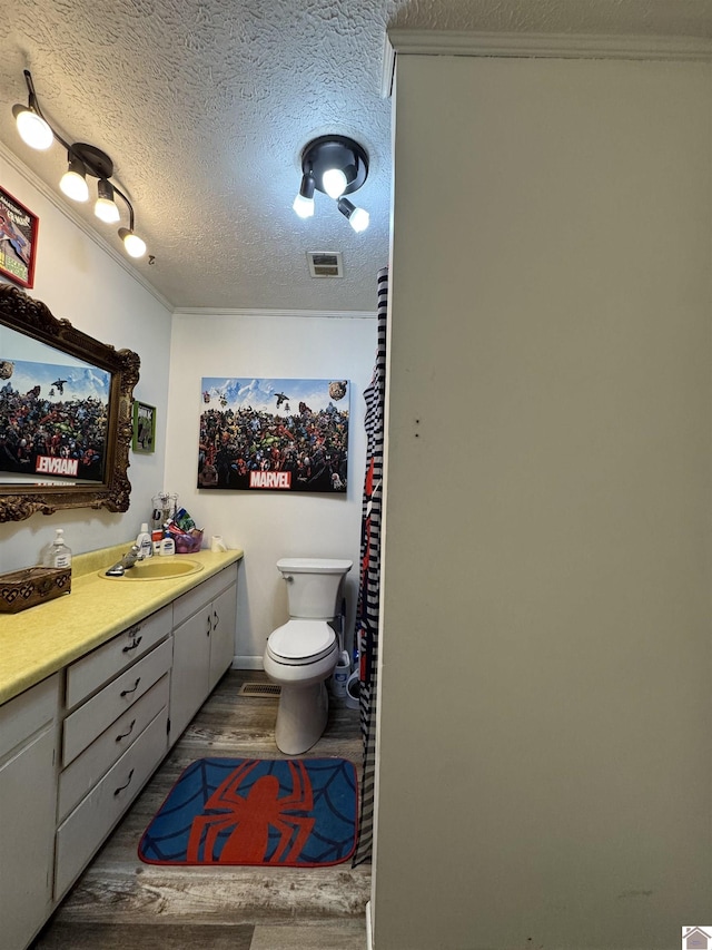 bathroom with toilet, wood finished floors, vanity, a textured ceiling, and visible vents