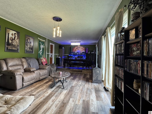living area featuring crown molding, a textured ceiling, an inviting chandelier, and wood finished floors
