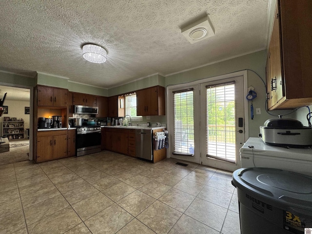 kitchen with a sink, stainless steel appliances, crown molding, light countertops, and light tile patterned floors