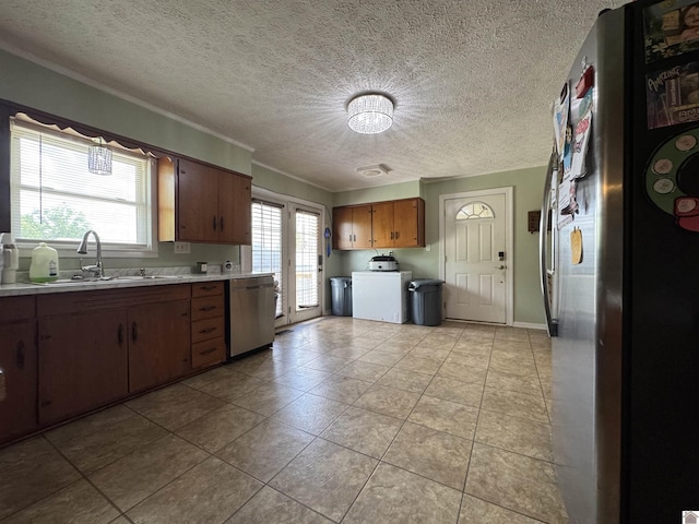 kitchen featuring a sink, washer / clothes dryer, a textured ceiling, light countertops, and appliances with stainless steel finishes