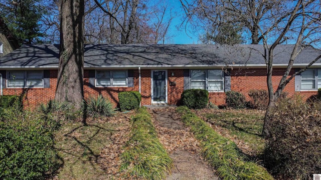 ranch-style house featuring brick siding and roof with shingles