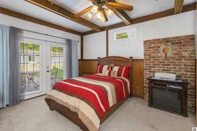 bedroom with light colored carpet, access to outside, beamed ceiling, wood walls, and a wainscoted wall