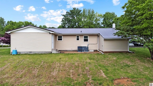 rear view of property with central air condition unit, a lawn, and metal roof