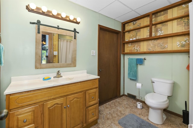 full bath featuring toilet, vanity, a paneled ceiling, and baseboards