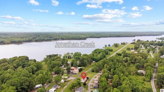 aerial view of property's location with a nearby body of water and a heavily wooded area