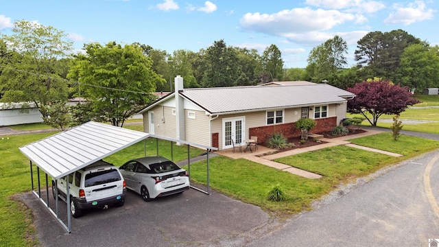ranch-style house with french doors, a detached carport, a chimney, a front lawn, and brick siding