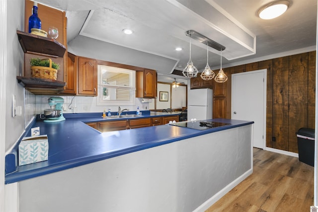 kitchen featuring freestanding refrigerator, dark countertops, a sink, brown cabinetry, and wood finished floors