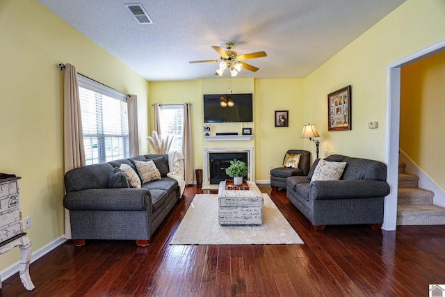 living room featuring ceiling fan, dark wood-style flooring, and a fireplace with flush hearth