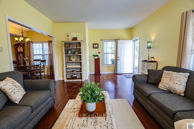 living room with a chandelier, dark wood-style floors, healthy amount of natural light, and baseboards