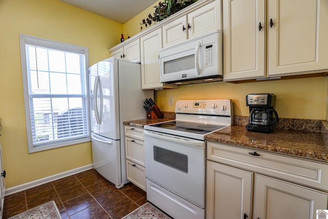 kitchen featuring white appliances, healthy amount of natural light, baseboards, and white cabinetry