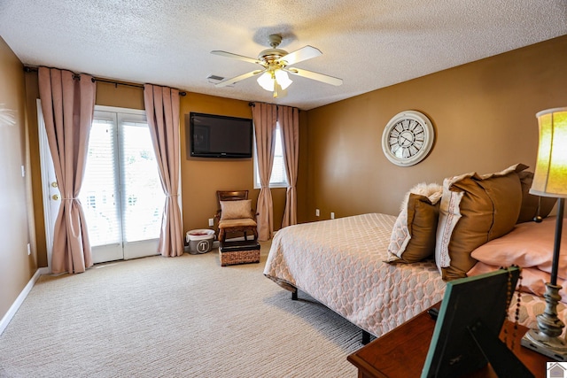 carpeted bedroom with access to exterior, a textured ceiling, multiple windows, and a ceiling fan
