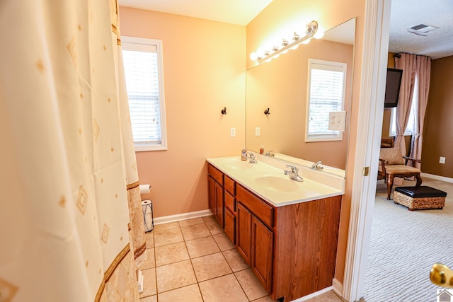 bathroom with double vanity, tile patterned flooring, baseboards, and a textured ceiling