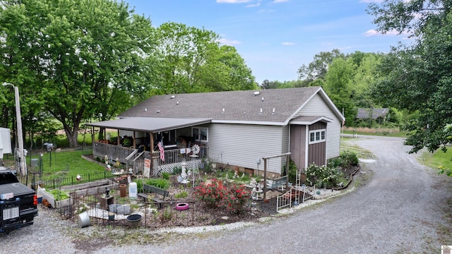 back of house featuring a shingled roof, fence, and view of scattered trees