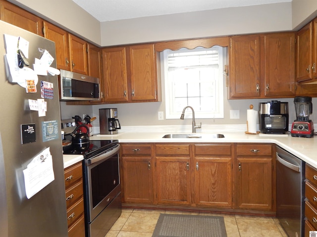 222 Ash St, Benton, KY 42025 - kitchen with appliances with stainless steel finishes, a sink, light countertops, brown cabinetry, and light tile patterned floors