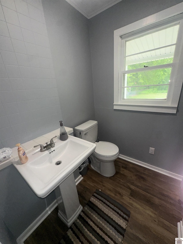 half bath featuring wood finished floors, toilet, ornamental molding, and baseboards
