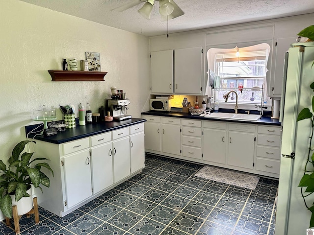 203 N 17th, Murray, KY 42071 - kitchen with freestanding refrigerator, a sink, dark countertops, a textured ceiling, and a textured wall