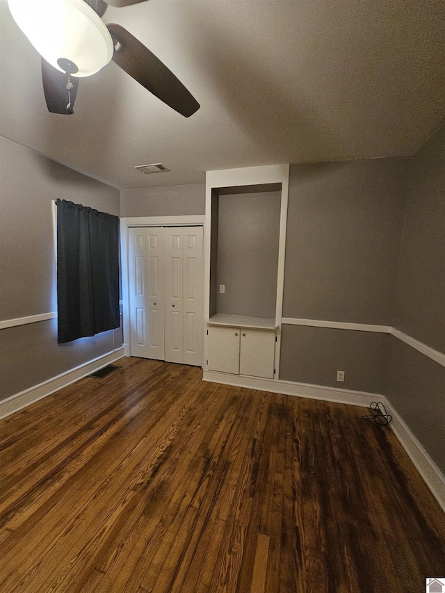 unfurnished bedroom featuring dark wood-style flooring, baseboards, ceiling fan, and a closet