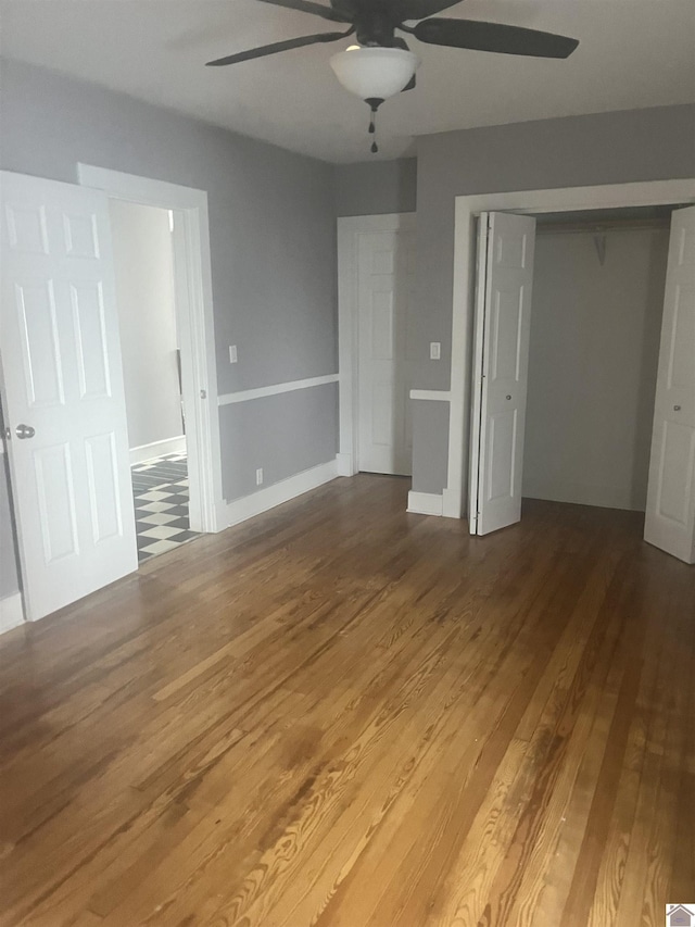 unfurnished bedroom featuring wood finished floors, a closet, and ceiling fan
