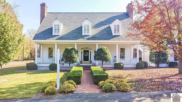 cape cod home featuring a chimney, a porch, a front lawn, and a high end roof