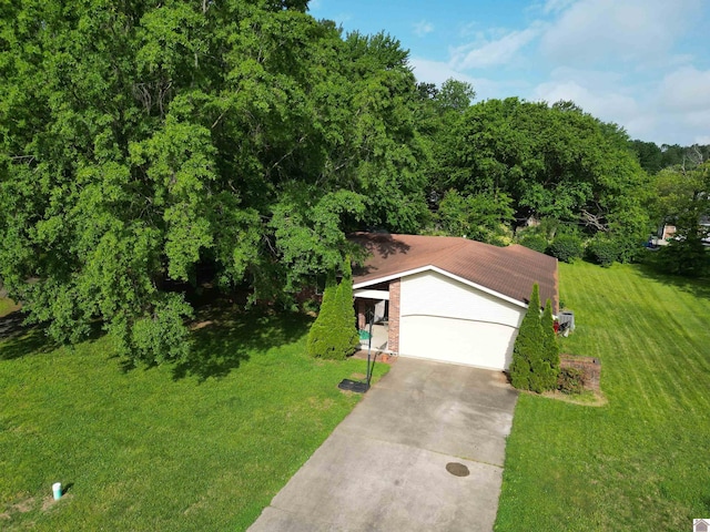view of front of house featuring driveway, a front yard, a forest view, and a garage