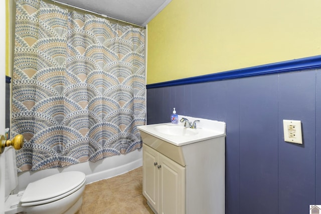 bathroom with toilet, vanity, tile patterned flooring, a decorative wall, and shower / bathtub combination with curtain