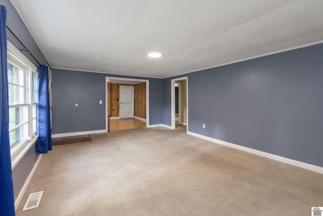 carpeted spare room featuring baseboards and crown molding