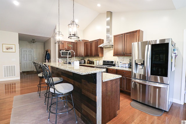 1300 Rocky Rd, Fancy Farm, KY 42039 - kitchen with appliances with stainless steel finishes, wall chimney exhaust hood, an island with sink, a breakfast bar, and decorative backsplash