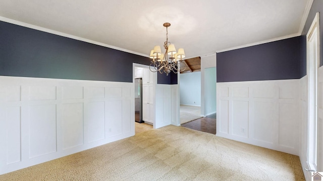 unfurnished dining area with a decorative wall, a chandelier, light carpet, crown molding, and a wainscoted wall