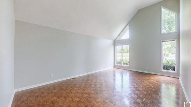 empty room featuring high vaulted ceiling and baseboards