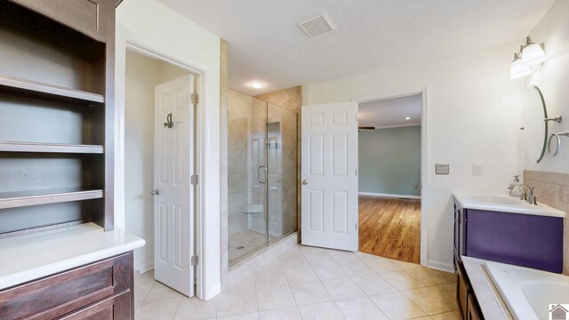 bathroom featuring a stall shower, tile patterned floors, vanity, baseboards, and a bath