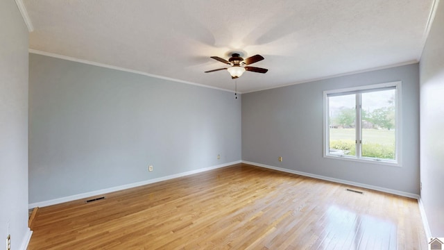 spare room featuring a ceiling fan, light wood-style flooring, baseboards, and crown molding