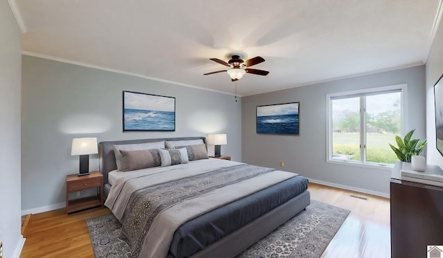bedroom with light wood-style flooring, baseboards, ornamental molding, and ceiling fan