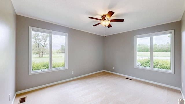 empty room featuring baseboards, a ceiling fan, ornamental molding, and light colored carpet