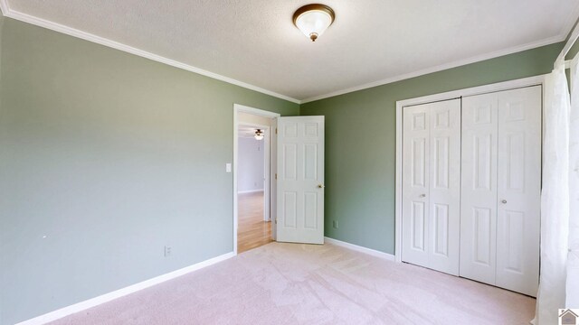 unfurnished bedroom with ornamental molding, light carpet, a closet, and baseboards