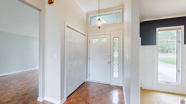 entrance foyer with baseboards, crown molding, and a high ceiling
