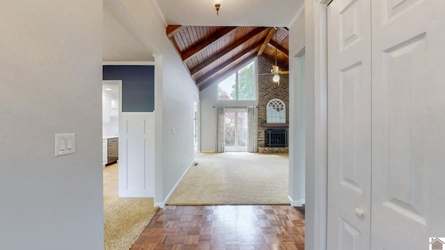 hallway featuring carpet floors, baseboards, high vaulted ceiling, beamed ceiling, and wood ceiling