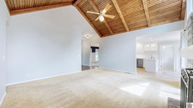 unfurnished living room featuring wood ceiling, high vaulted ceiling, light colored carpet, baseboards, and a ceiling fan