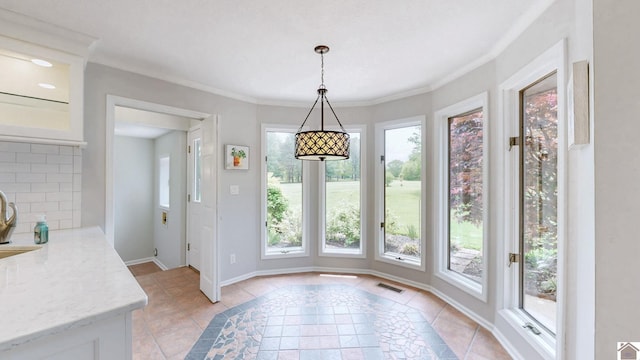 unfurnished dining area featuring plenty of natural light, baseboards, inlaid floor details, a sink, and crown molding