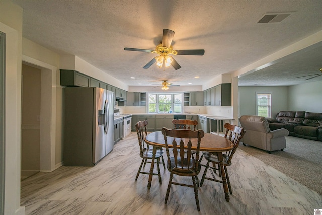 dining area featuring a textured ceiling, a ceiling fan, and light wood-style flooring