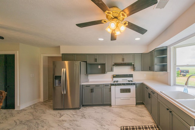 kitchen featuring stainless steel fridge, white gas range oven, open shelves, a sink, and under cabinet range hood