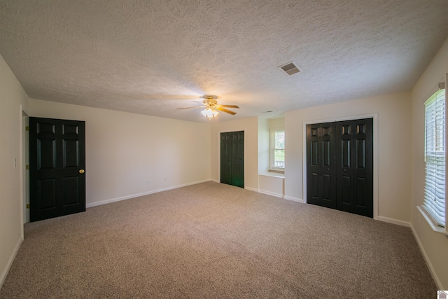 carpeted foyer entrance featuring a ceiling fan, a textured ceiling, and baseboards
