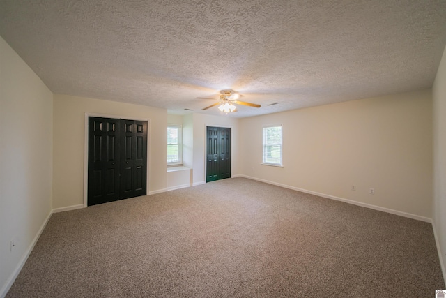 carpeted empty room with baseboards, a textured ceiling, and ceiling fan