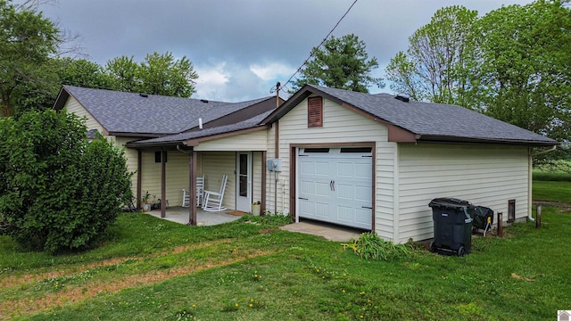rear view of house with a lawn, a shingled roof, and a garage