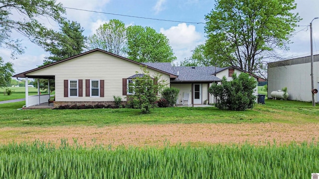 back of property with a lawn and a shingled roof