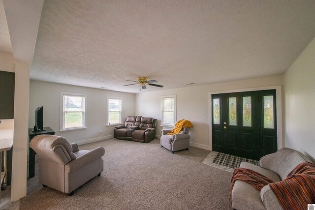 living area featuring carpet flooring, baseboards, and ceiling fan