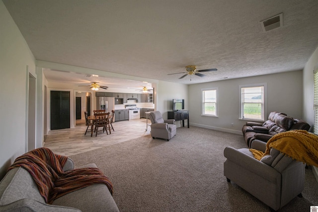 living room featuring light colored carpet, baseboards, and a ceiling fan