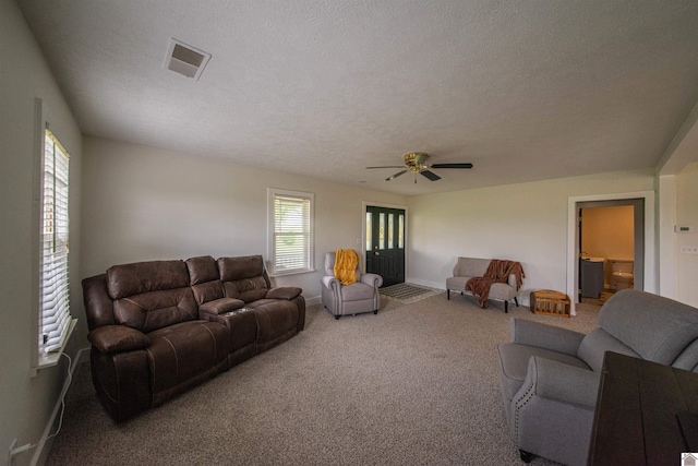 living area featuring plenty of natural light, a textured ceiling, carpet flooring, a ceiling fan, and baseboards